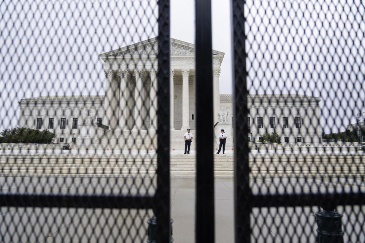 FILE - In this Sept. 17, 2021 file photo U.S. Capitol police officers walk near fencing around the Supreme Court in Washington. Twenty-five media and transparency groups are asking the Washington Supreme Court to allow the release of the names of the Seattle police officers who attended events in Washington D.C. on Jan. 6 -- the day of the insurrection. The Reporters Committee for the Freedom of the Press and the news organizations are asking the court to deny an injunction filed by the officers that seeks to block the release of public records that identify the officers.