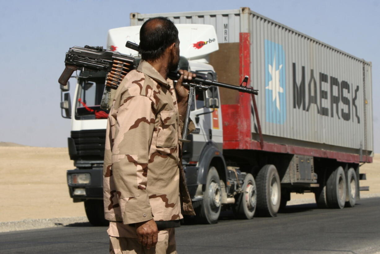 FILE - In this Oct. 27, 2010, file photo a private security contractor watches a NATO supply truck drive past in the province of Ghazni, south-west of Kabul, Afghanistan. Military contractors got up to half of the $14 trillion spent by the Pentagon since 9/11, a study by Brown University's Costs of War project and the Center for International Policy said Monday, Sept. 13, 2021.