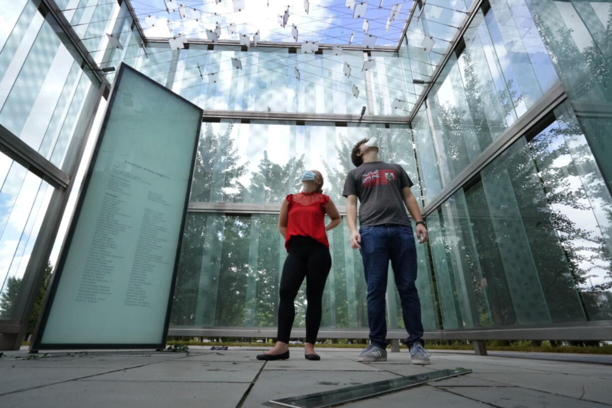 Chloe Taub and Anthony Brobenzano, of Hollywood, Fla., look at the 9/11 memorial at Logan International Airport, Thursday, Aug. 19, 2021, in Boston. The two were the only visitors during a three-hour span that afternoon. Tucked in a grove of ginkgo trees, the glass cube at Logan Airport pays tribute to those lost aboard the two jetliners that took off from Boston and were hijacked by terrorists who flew them into the World Trade Center towers. But it's mostly silent homage. The memorial etched with the names of those who perished aboard American Airlines Flight 11 and United Airlines Flight 175 draws few visitors.