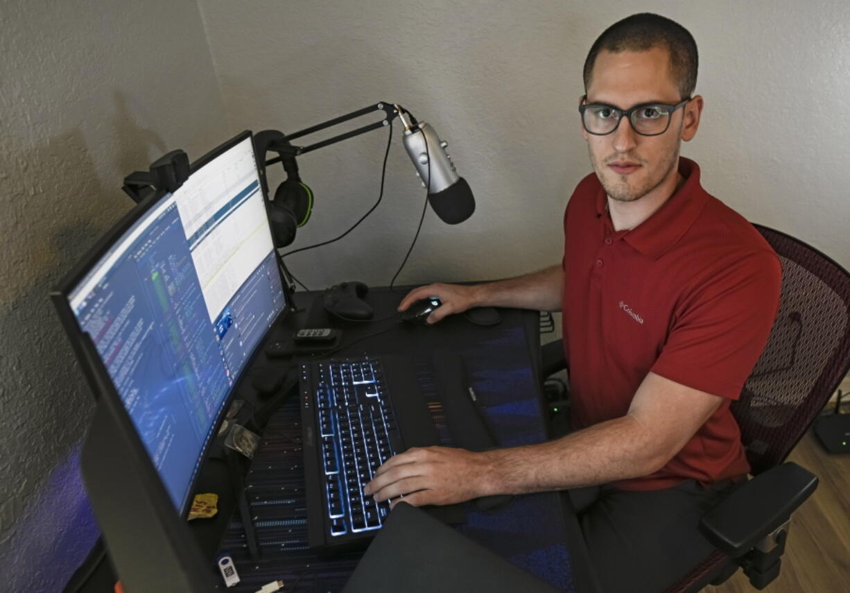 In this Sept. 20, 2021, photo Austin Moody poses for a photo as he sits a his home work station in Tampa, Fla. Moody, the Michigan native, got a scholarship from the Department of Defense that required working for the agency at least a year after graduating. Moody said he understands that state governments don't have the kind of money that federal agencies or private companies spend on recruiting and generous salaries.