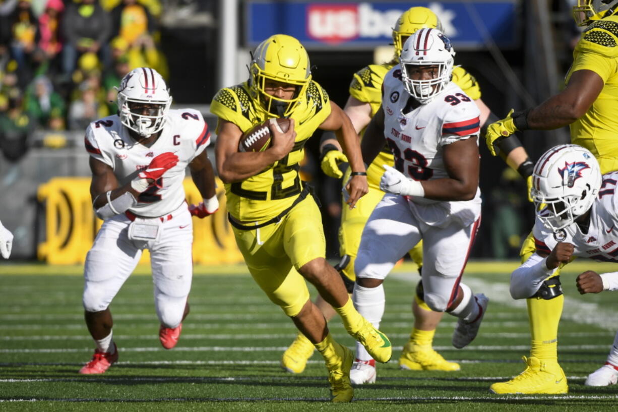 Oregon running back Travis Dye (26) runs past Stony Brook defensive lineman Casey Williams (2) and Stony Brook defensive lineman Dakar Edwards (93) during the first quarter of an NCAA college football game Saturday, Sept. 18, 2021, in Eugene, Ore.