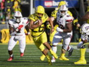 Oregon running back Travis Dye (26) runs past Stony Brook defensive lineman Casey Williams (2) and Stony Brook defensive lineman Dakar Edwards (93) during the first quarter of an NCAA college football game Saturday, Sept. 18, 2021, in Eugene, Ore.