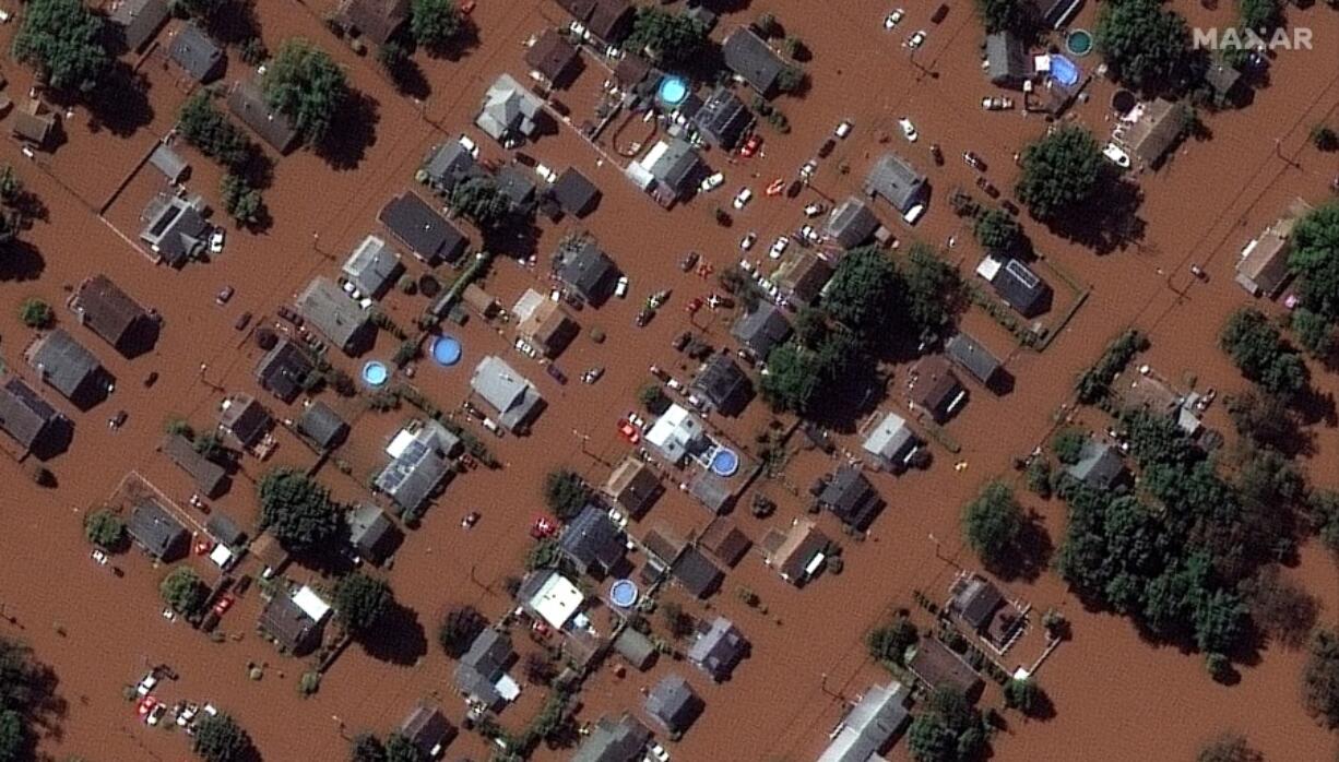 In a satellite image provided by Maxar Technologies, homes along Boessel Ave., in Manville, N.J. are surrounded by floodwaters Thursday, Sept.