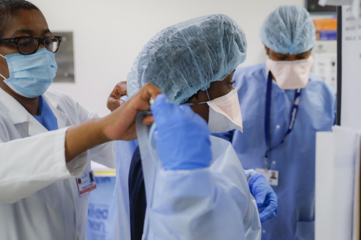 FILE - In this Wednesday, May 27, 2020 file photo, Medical personnel adjust their personal protective equipment while working in the emergency department at NYC Health + Hospitals Metropolitan in New York. Hospitals and nursing homes in New York are bracing for the possibility that a statewide COVID-19 vaccine mandate for health care workers could lead to staff shortages when it takes effect Monday, Sept. 27, 2021. Doctors and nurses -- and also support staff, like food service workers and cleaners -- have been given until Sept. 27 to get at least their first vaccine shot in one of the nation's most aggressive plans to protect patients.