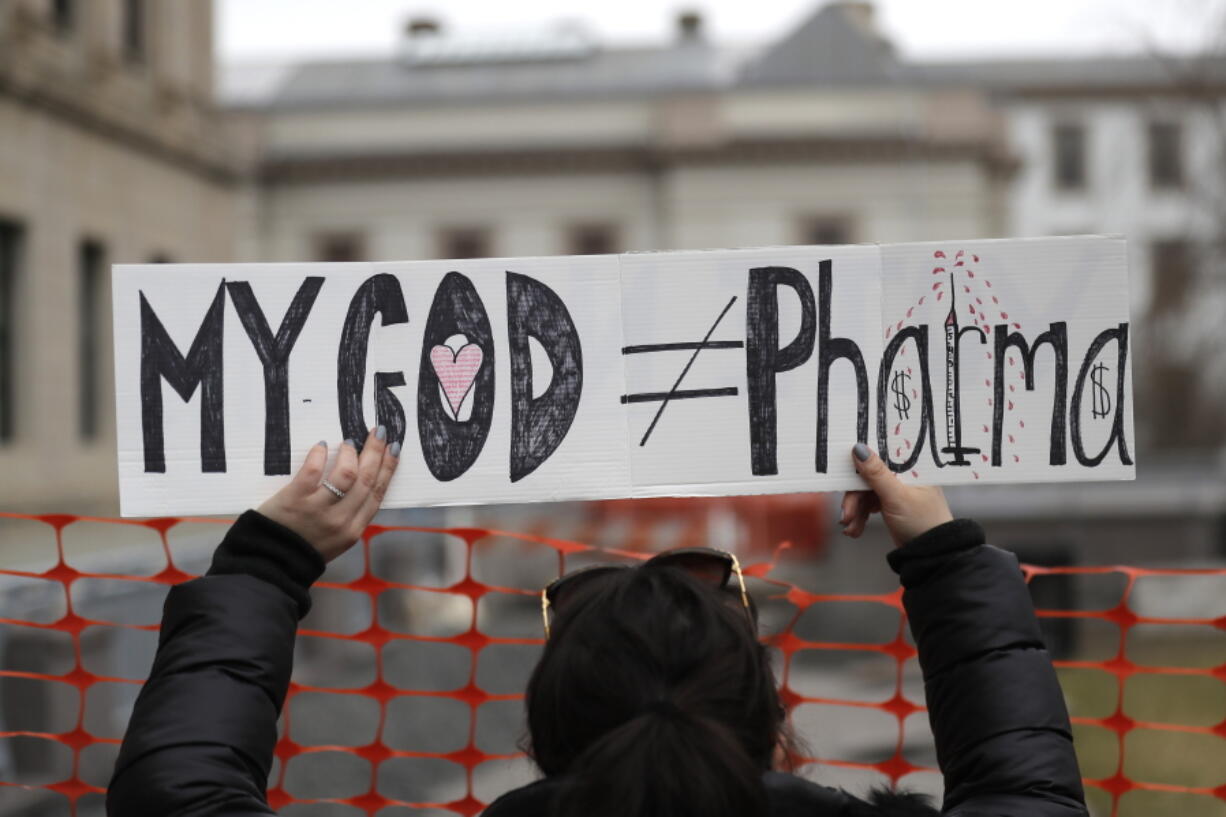 FILE - In this Jan. 13, 2020, file photo, a woman holds a sign during a protest at the state house in Trenton, N.J. Religious objections, once used only sparingly around the country to get exempted from various required vaccines, are becoming a much more widely used loophole against the COVID-19 shot.