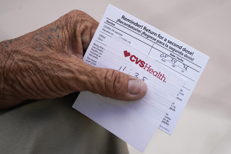 A man holds his vaccination reminder card after having received his first shot at a pop-up vaccination site.