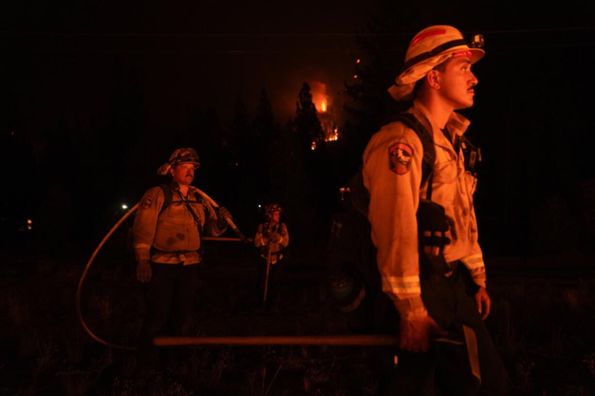 FILE - In this Wednesday, Sept. 1, 2021, file photo, firefighters are lit by a backfire set to prevent the Caldor Fire from spreading near South Lake Tahoe, Calif. Thousands of wildfires burn in the U.S. each year, and each one requires firefighters to make quick decisions, often in difficult conditions like high winds and lightning. Crews and managers must determine when to bring in aircraft, what time of day is best to battle flames, whether to evacuate residents and even if certain fires should be extinguished at all. (AP Photo/Jae C.