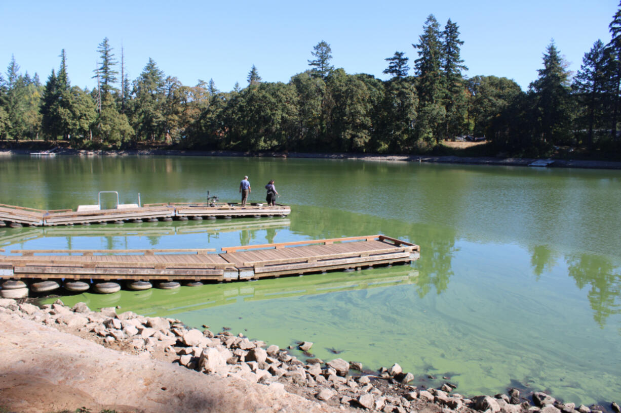 People stand on a Lacamas Lake pier on Sept. 25. The county placed "danger" advisories around the Camas lake earlier this year after finding high concentrations of toxic blue-green algae.