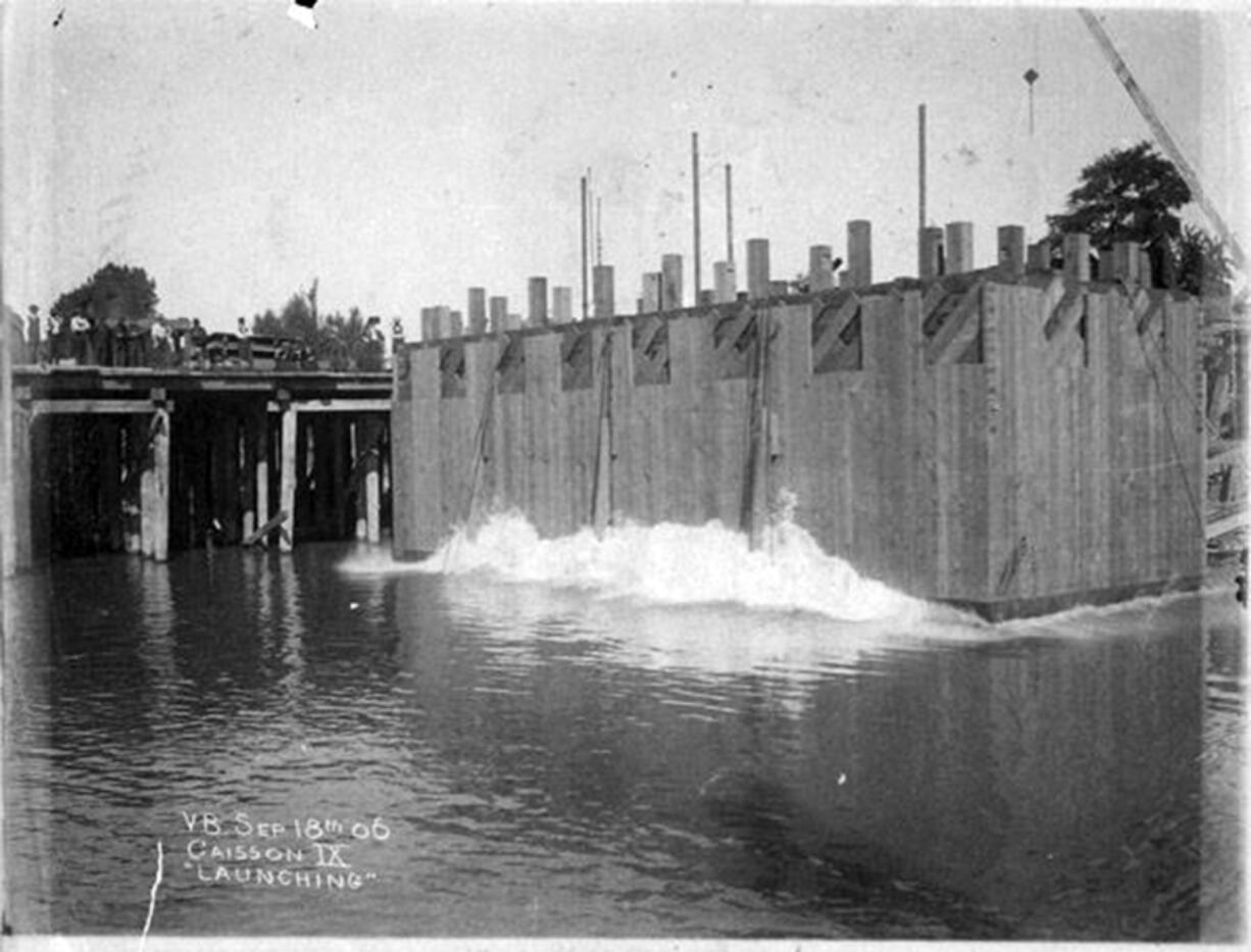 This concrete box allowed workers access to the floor of the Columbia River to anchor and build the bridge piers holding up the Portland-Vancouver railway bridge connecting Oregon and Washington. This 1906 photo shows the caisson (box) being lowered into the river. About two years later, regularly scheduled trains crossed the two-rail bridge daily in both directions, north and southbound.