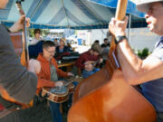 From left: Roger Vanderveen, seated, on dobro guitar; Nate Hendricks, 16, on mandolin; and Jon Rand on the upright bass perform during the 21st annual BirdFest & Bluegrass festival Saturday at the Park Food Cart Pod in Ridgefield.