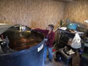 Debbie Boe, owner of Edible Acres Farm in Ridgefield, feeds koi swimming in the fish tank in a room near her greenhouse on Friday morning. Waste from the koi is circulated through planting beds to grow food in a process known as aquaponics.