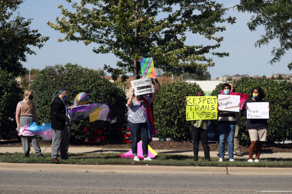 Protesters hold signs Sept. 24 across from St. Francis High School in Wheaton, Ill., calling for recognition of nontraditional personal pronouns used by queer and transgender students.