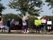 Protesters hold signs Sept. 24 across from St. Francis High School in Wheaton, Ill., calling for recognition of nontraditional personal pronouns used by queer and transgender students.