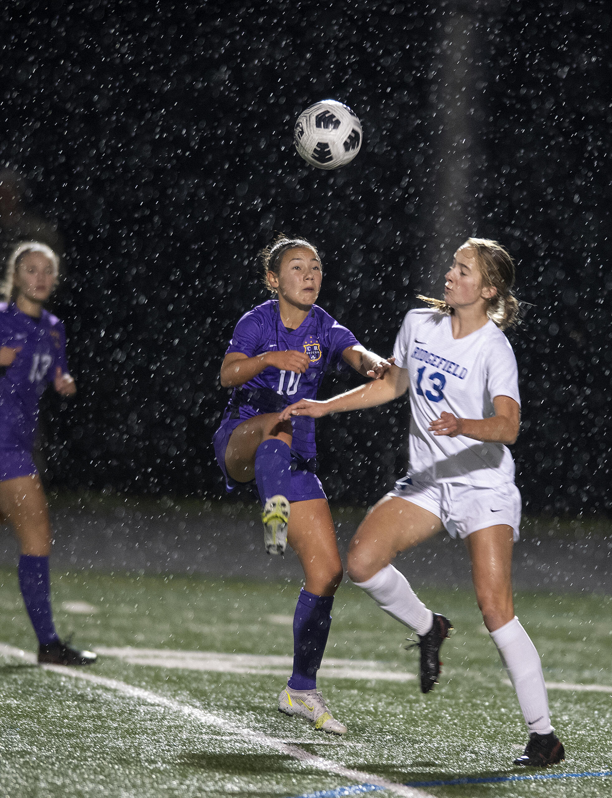 Columbia River's Andie Buckley (10) and Ridgefield's Cameron Jones (13) handle a header in the first half at Columbia River High School on Tuesday night, Oct. 12, 2021.