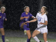 Columbia River's Andie Buckley (10) and Ridgefield's Cameron Jones (13) handle a header in the first half at Columbia River High School on Tuesday night, Oct. 12, 2021.