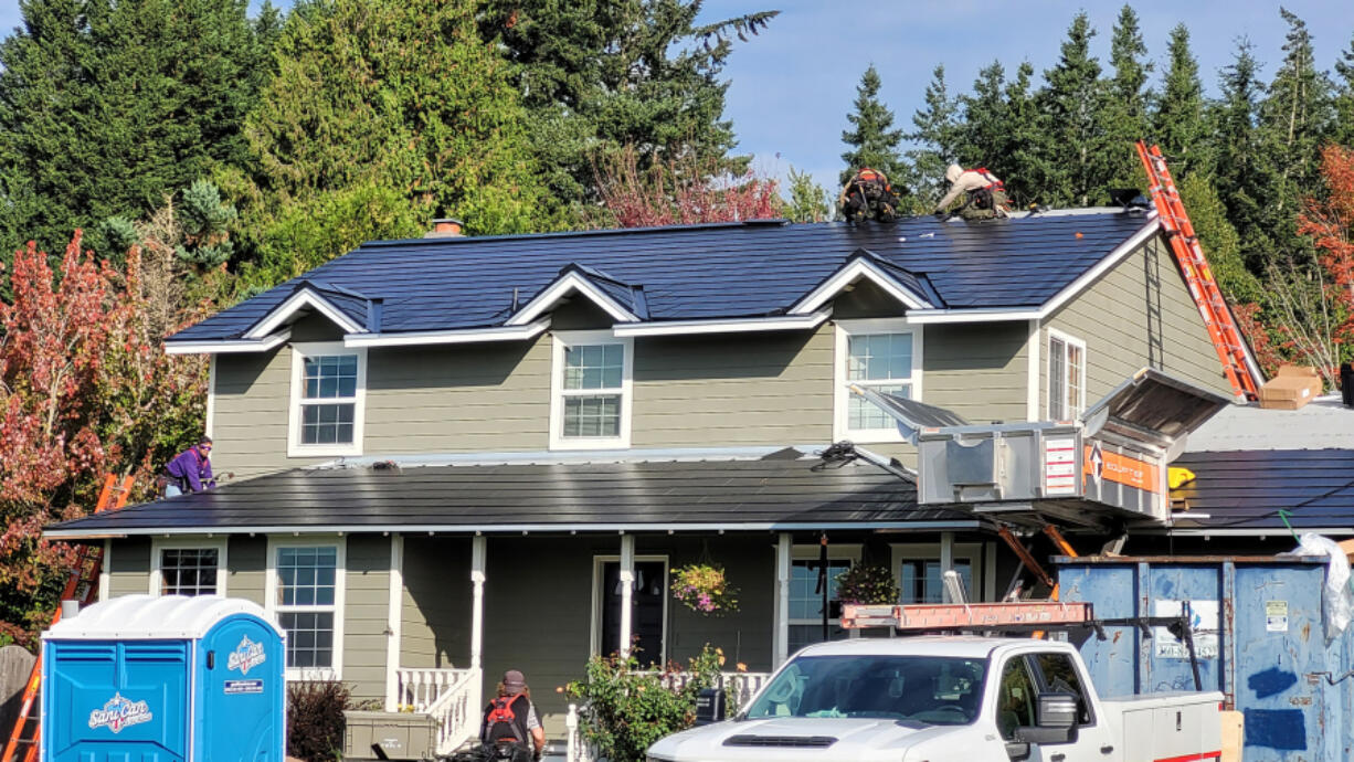 Crews install a new Tesla roof at Dave Miller's Camas home. At top: The glass photovoltaic tiles in a Tesla roof are stronger than standard roofing tiles, according to the company.