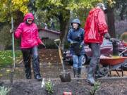 Suzanne Mickelson, left, and Ellen Zacny, center, laugh while planting foliage in the Riveridge Neighborhood cul-de-sac island on Saturday morning.