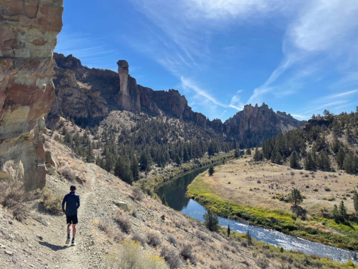 A trail runner navigates the River Trail along the Crooked River at Smith Rock State Park.