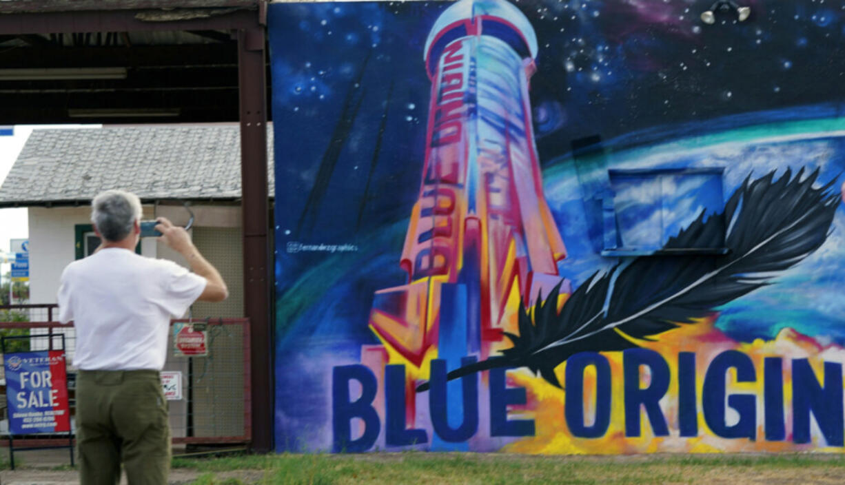 Gene Walker, of Denison, Texas, makes a photo of a Blue Origin mural on a building for sale in Van Horn, Texas, Tuesday Oct. 12, 2021. Today's launch has been pushed to Wednesday due to weather.