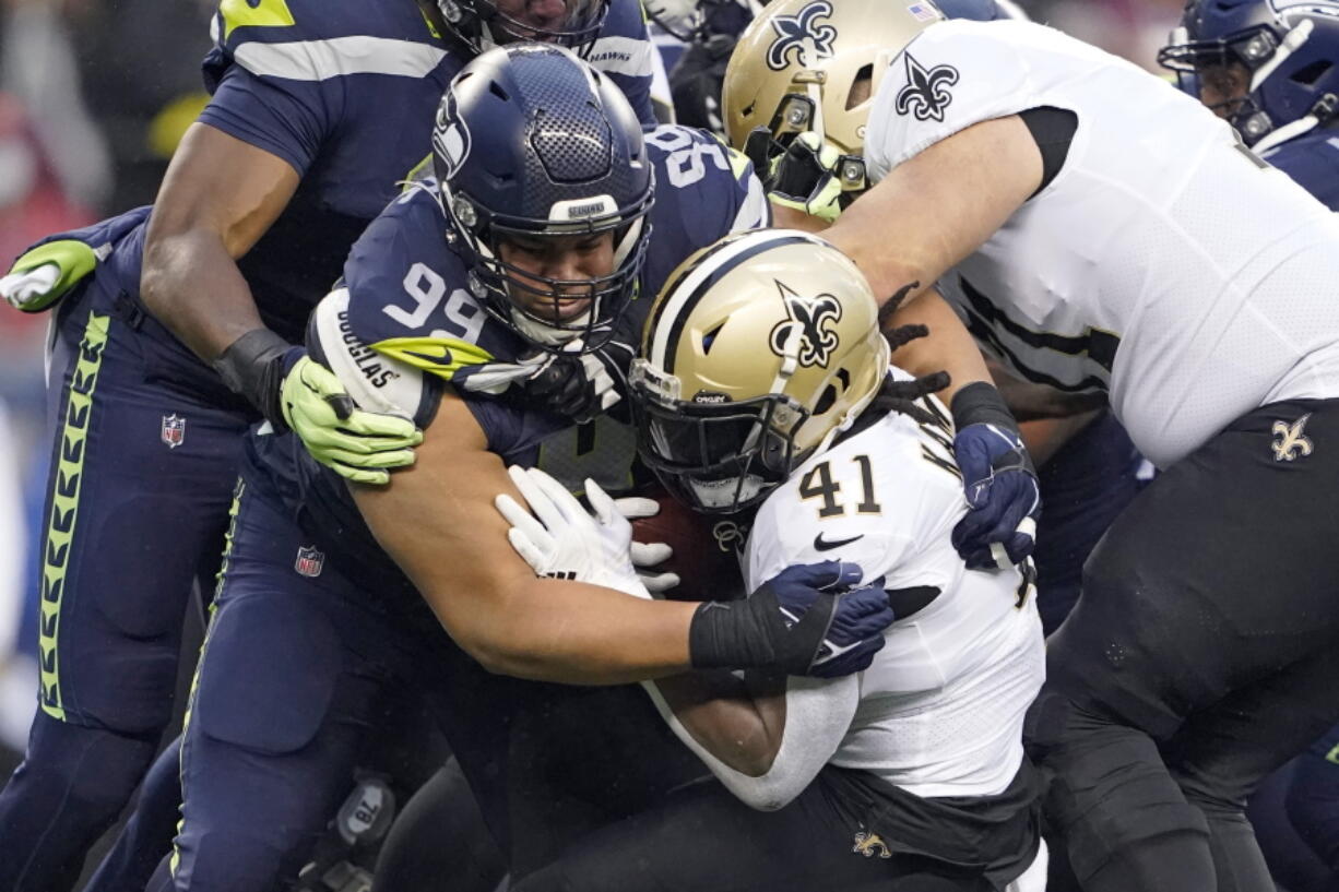 Seattle Seahawks defensive end Rasheem Green (94) brings down New Orleans Saints running back Alvin Kamara (41) during the first half of an NFL football game, Monday, Oct. 25, 2021, in Seattle. (AP Photo/Ted S.