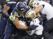 Seattle Seahawks defensive end Rasheem Green (94) brings down New Orleans Saints running back Alvin Kamara (41) during the first half of an NFL football game, Monday, Oct. 25, 2021, in Seattle. (AP Photo/Ted S.