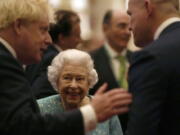 Britain's Queen Elizabeth II and Prime Minister Boris Johnson, left, greet guests at a reception for the Global Investment Summit in Windsor Castle, Windsor, England, Tuesday, Oct. 19, 2021.