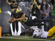 Oregon running back Travis Dye (26) dives into the end zone over California safety Daniel Scott (32) during the second quarter of an NCAA college football game Friday, Oct. 15, 2021, in Eugene, Ore.