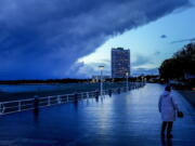 A woman walks on the promenade at the Baltic Sea in Travemuende, northern Germany, Thursday, Oct.21, 2021. Northern Germany was hit by storm and heavy rain falls.