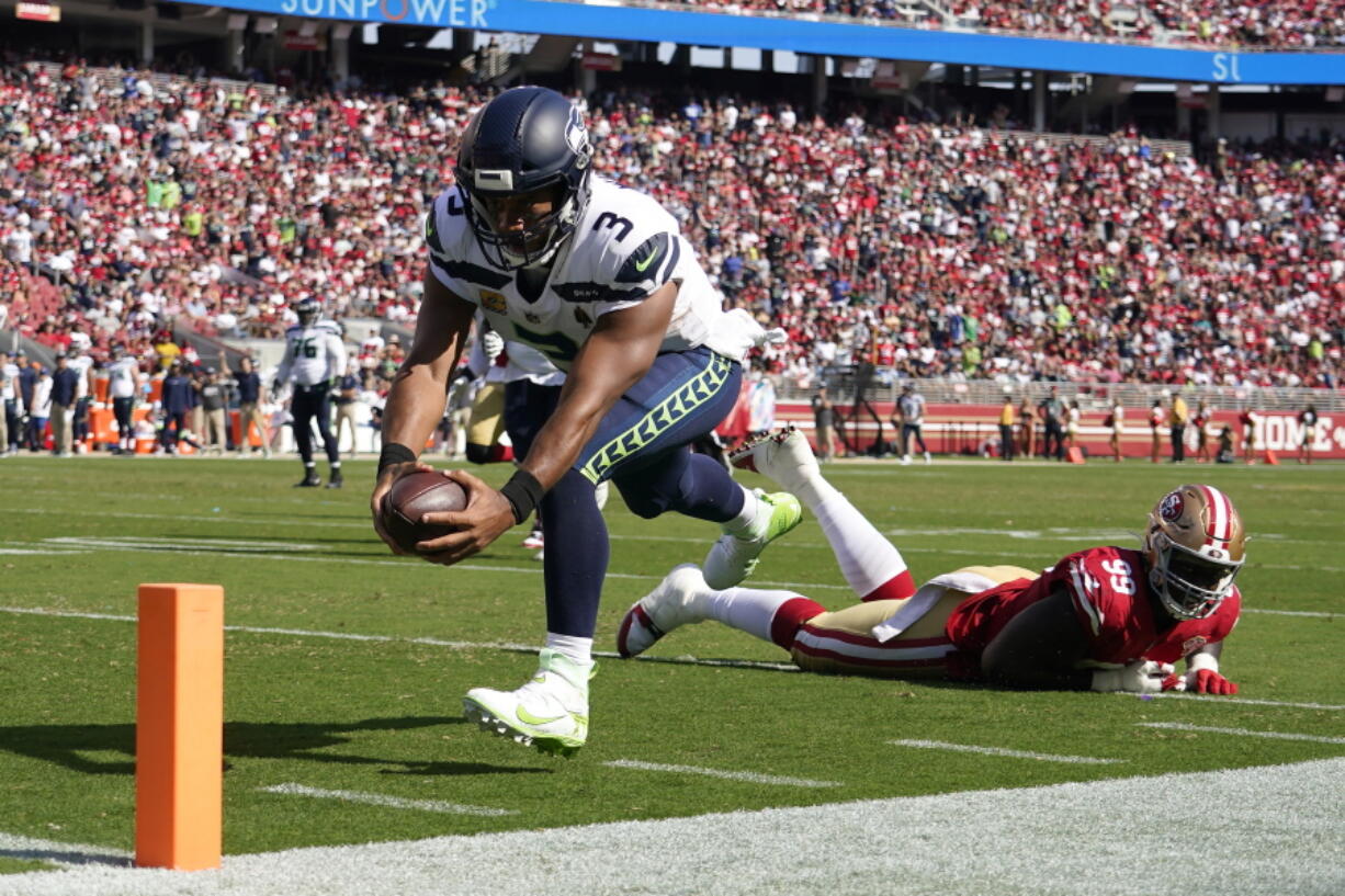 Seattle Seahawks quarterback Russell Wilson (3) runs for a touchdown past San Francisco 49ers defensive tackle Javon Kinlaw (99) during the second half of an NFL football game in Santa Clara, Calif., Sunday, Oct. 3, 2021.