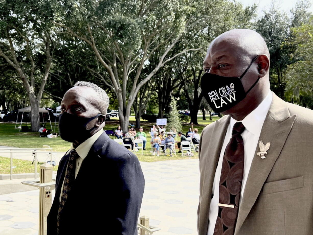 Ahmaud Arbery's father Marcus Arbery, left, heads into the Glynn County Courthouse in Brunswick, Ga with his attorney Benjamin Crump on Monday, Oct. 18, 2021. Jury selection got underway with hundreds of people ordered to report for what could be a long, laborious effort to find jurors to hear the trial of three white men charged with fatally shooting Ahmaud Arbery as he was running in their neighborhood. (AP Photo/Lewis M.