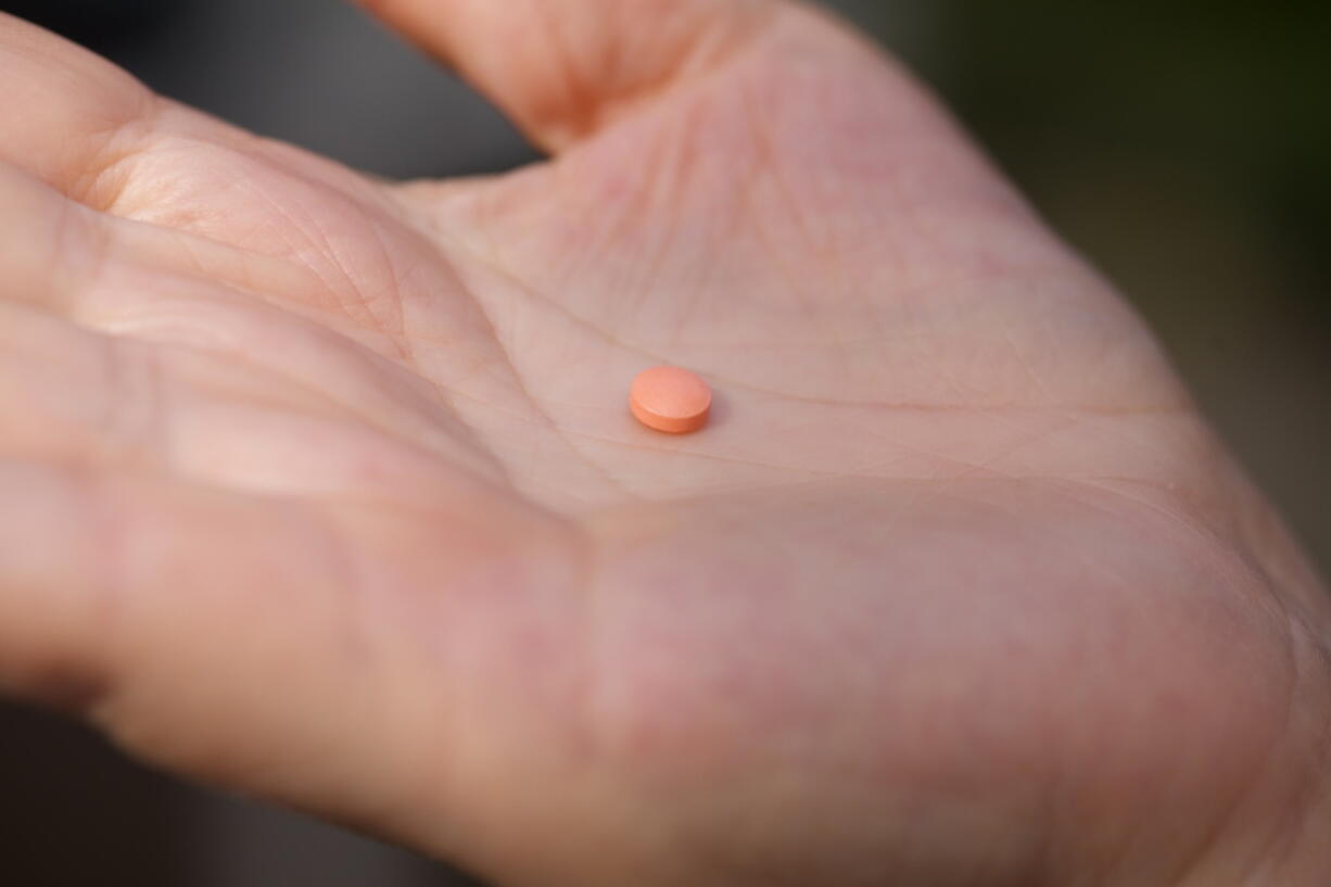 A woman holds an aspirin pill in the Brooklyn borough of New York on Friday, Oct. 15, 2021. According to the U.S. Preventive Services Task Force's preliminary updated advice released on Tuesday, Oct. 12, 2021, older adults without heart disease shouldn't take daily aspirin to prevent a first heart attack or stroke. (AP Photo/Emma H.