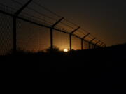 The sun sets behind a border fence separating Del Rio, Texas, and Ciudad Acuna, Mexico, Thursday, Sept. 23, 2021. Each year, the border communities that sit across the Rio Grande from one another come together to celebrate the Fiesta de la Amistad.