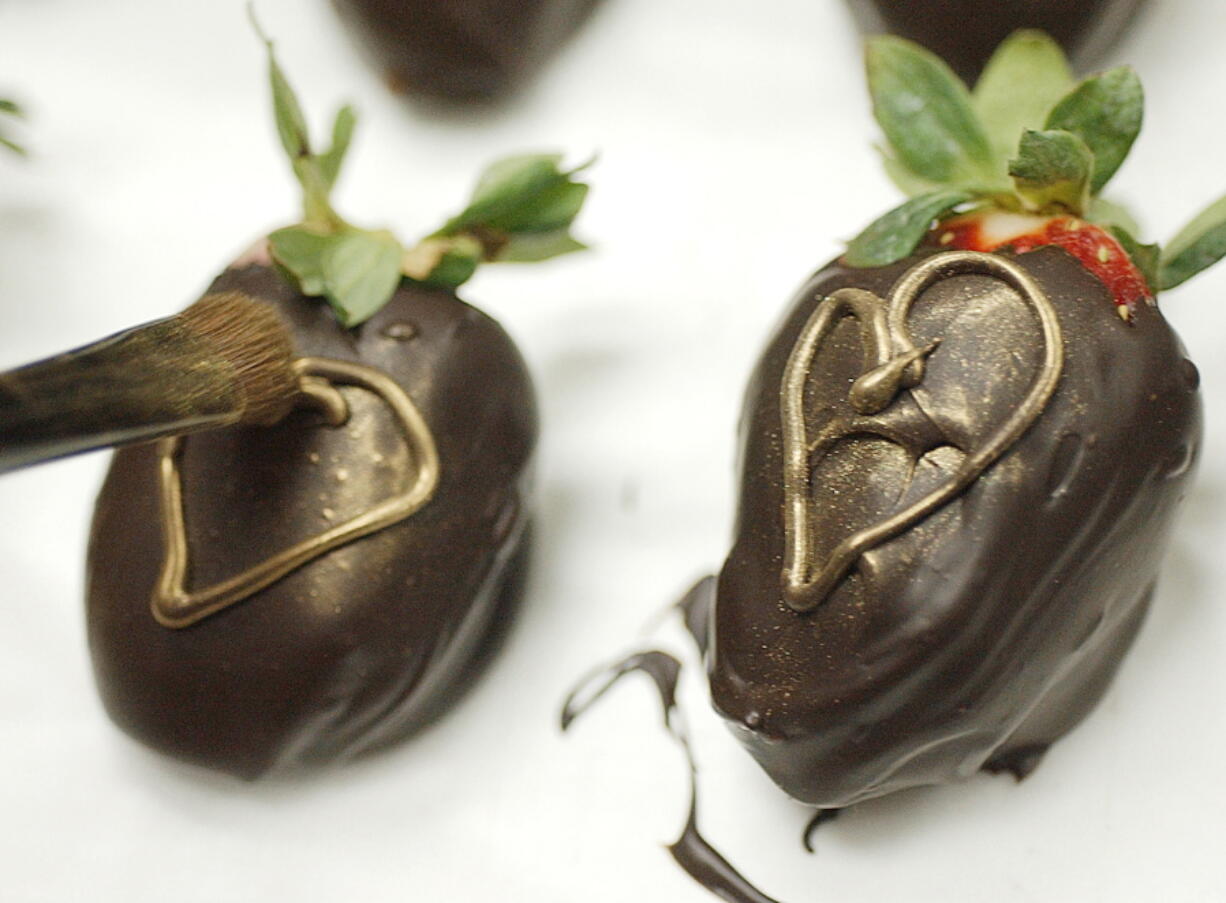 A candy shop owner applies gold luster sugar dust to chocolate-dipped strawberries at the family's business in Lebanon, Pa. A report by the Centers for Disease Control and Prevention says luster dusts that are safe to eat are typically marked as edible, but that others might contain heavy metals and shouldn't be used on food.