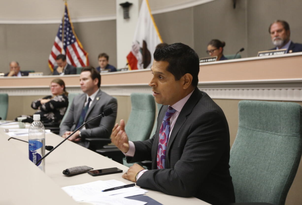 FILE -  In this Aug. 12, 2019 file photo Assemblyman Miguel Santiago, D-Los Angeles, questions State Auditor Elaine Howle about an audit her office performed, during a hearing in Sacramento, Calif. Gov. Gavin Newsom signed a measure authored by Santiago that will let some adult children add their parents as dependents on their health insurance plans. The law would not apply to people who get health insurance through their work and only apply to people who purchase their own insurance on the individual market.