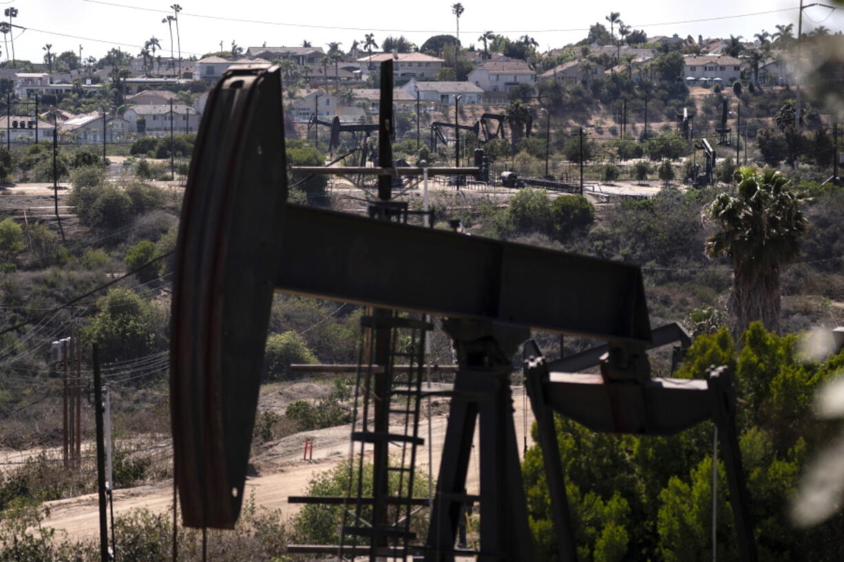 FILE - In this May 18, 2021, file photo, homes sit on a hill behind pump jacks operating at the Inglewood Oil Field in Los Angeles. California's oil regulator wants to ban new oil and gas drilling within 3,200 feet of schools, homes and hospitals to protect public health. The draft rule released Thursday, Oct. 21, 2021, would be the nation's largest buffer zone between drilling and community sites if adopted. (AP Photo/Jae C.