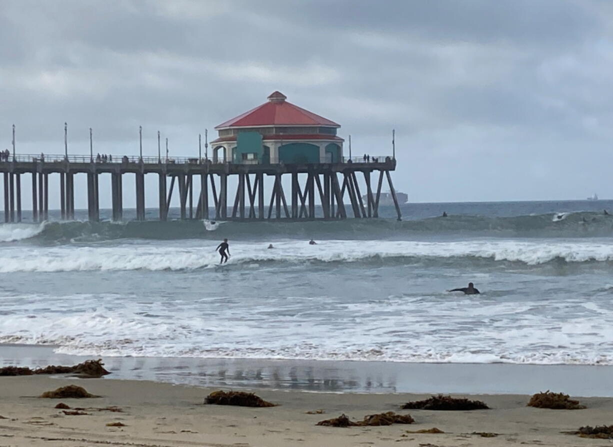 Surfers and swimmers return to the Huntington Beach pier waves since the crude oil spill at the California beach, Monday, Oct. 11, 2021. The reopening of Huntington Beach, dubbed "Surf City USA," came far sooner than many expected after a putrid smell blanketed the coast and blobs of crude began washing ashore.