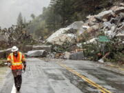 Caltrans maintenance supervisor Matt Martin walks by a landslide covering Highway 70 in the Dixie Fire zone on Sunday, Oct. 24, 2021, in Plumas County, Calif. Heavy rains blanketing Northern California created slide and flood hazards in land scorched during last summer's wildfires.