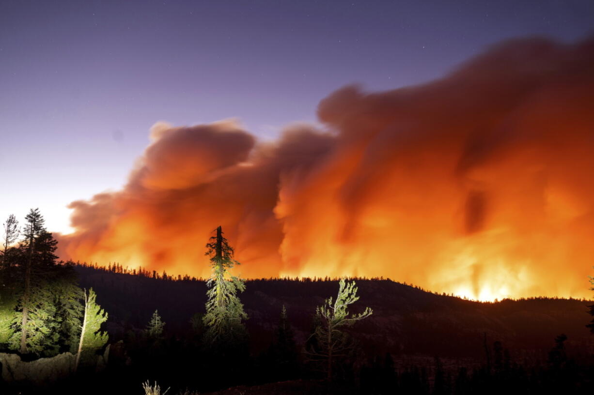 FILE - In this Aug. 29, 2021, file photo, taken with a long camera exposure, the Caldor Fire burns in Eldorado National Forest, Calif. The 2-month-old California wildfire that threatened the Lake Tahoe resort region during the summer has been declared 100% contained. The fire reached the containment milestone late Wednesday, Oct. 20, 2021.