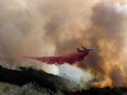 FILE - In this Oct. 13, 2021, file photo, an air tanker drops retardant on a wildfire in Goleta, Calif. Firefighters persisted in making progress Saturday, Oct. 17, against a wildfire burning for a sixth day in Southern California coastal mountains. The Alisal Fire in the Santa Ynez Mountains west of Santa Barbara grew only slightly since Friday to nearly 27 square miles (69 square kilometers). It was 50% contained. (AP Photo/Ringo H.W.