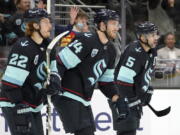 Seattle Kraken defenseman Jamie Oleksiak (24) reacts with teammates Mason Appleton (22) and Mark Giordano (5) after Oleksiak assisted Kraken's Brandon Tanev on a goal scored against the Montreal Canadiens during the first period of an NHL hockey game, Tuesday, Oct. 26, 2021, in Seattle. (AP Photo/Ted S.