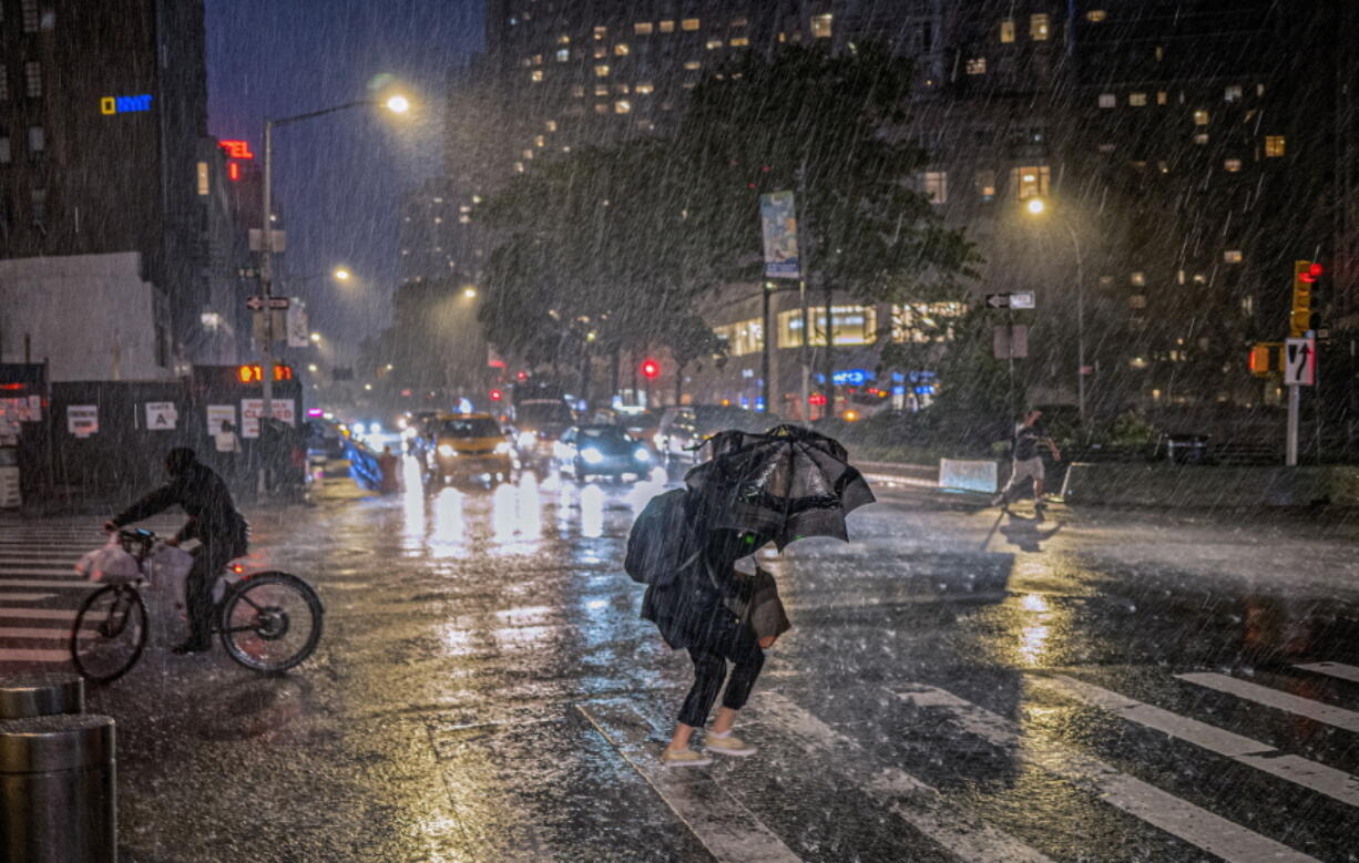 FILE - People travel through a torrential downpour caused from the remnants of Hurricane Ida, near Columbus Circle Wednesday Sept. 1, 2021. As weather becomes more extreme and unpredictable caused by climate change, transit officials say that more needs to be done to prepare the East Coast's vital transit systems.