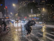 FILE - People travel through a torrential downpour caused from the remnants of Hurricane Ida, near Columbus Circle Wednesday Sept. 1, 2021. As weather becomes more extreme and unpredictable caused by climate change, transit officials say that more needs to be done to prepare the East Coast's vital transit systems.