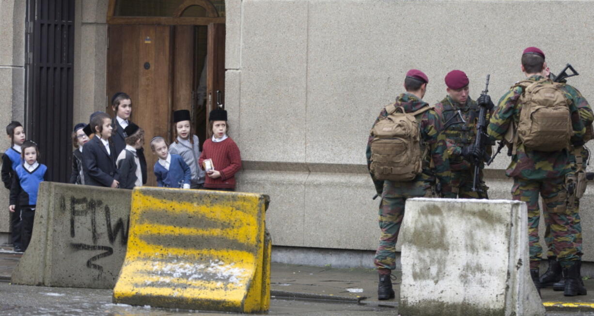 FILE - In this Saturday, Jan. 24, 2015 file photo, young Jewish children look at Belgian soldiers as they patrol during religious services in Antwerp, Belgium. The European Union unveiled Tuesday, Oct. 5, 2021 a new strategy to combat growing antisemitism in Europe with plans to better tackle hate speech, raise awareness about Jewish life, protect places of worship and ensure that the Holocaust is not forgotten.