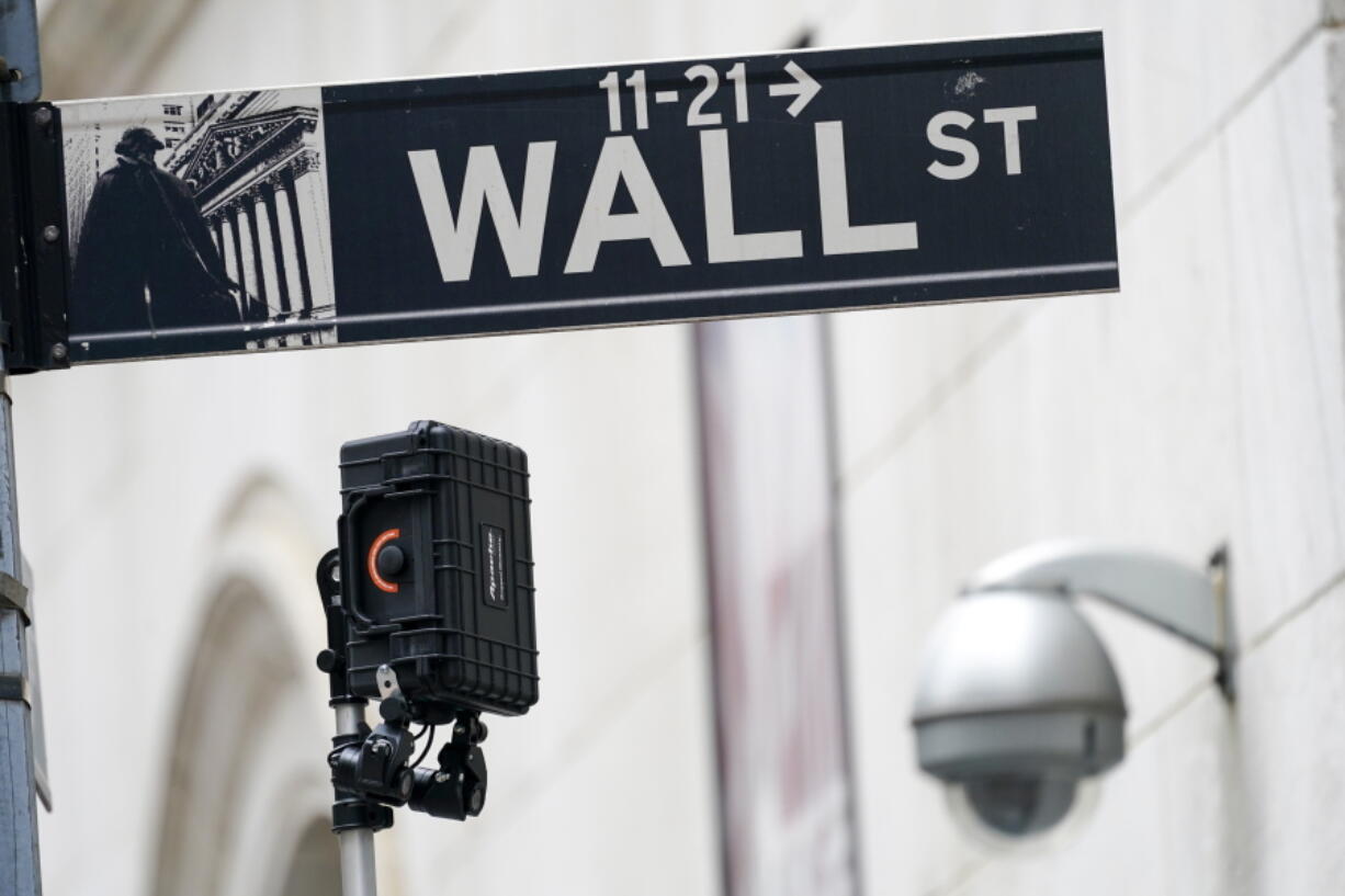 FILE - A Wall Street sign is seen next to surveillance equipment outside the New York Stock Exchange, Tuesday, Oct. 5, 2021, in New York. Stocks fell in morning trading Wednesday, Oct. 6, 2021 as Wall Street undergoes a bout of volatility, driven in part by big swings in technology companies. The S&P 500 fell 0.8%. The benchmark index has risen or fallen by more than 1% the past four days. The Dow Jones Industrial Average slipped 1% and the Nasdaq fell 0.6%. International markets also sold off, with exchanges in Japan, South Korea, Germany and France all dropping more than 1%.