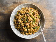 This image released by Milk Street shows a recipe for harissa-spiced pasta with chicken and green beans.