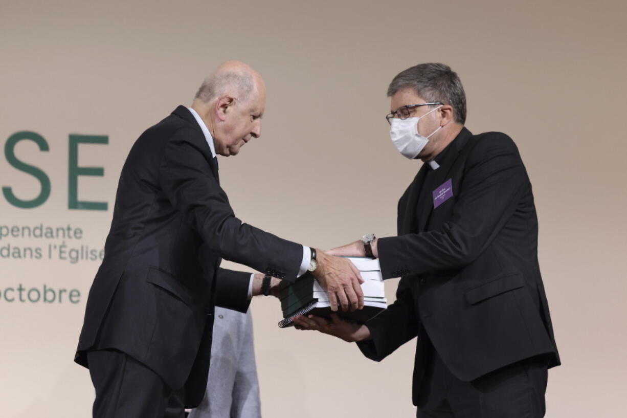 Commission president Jean-Marc Sauve, left, hands copies of the report to Catholic Bishop Eric de Moulins-Beaufort, president of the Bishops' Conference of France (CEF), during the publishing of a report by an independant commission into sexual abuse by church officials (Ciase), Tuesday, Oct. 5, 2021, in Paris. A major French report released Tuesday found that an estimated 330,000 children were victims of sex abuse within France's Catholic Church over the past 70 years, in France's first major reckoning with the devastating phenomenon.