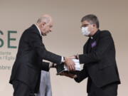 Commission president Jean-Marc Sauve, left, hands copies of the report to Catholic Bishop Eric de Moulins-Beaufort, president of the Bishops' Conference of France (CEF), during the publishing of a report by an independant commission into sexual abuse by church officials (Ciase), Tuesday, Oct. 5, 2021, in Paris. A major French report released Tuesday found that an estimated 330,000 children were victims of sex abuse within France's Catholic Church over the past 70 years, in France's first major reckoning with the devastating phenomenon.