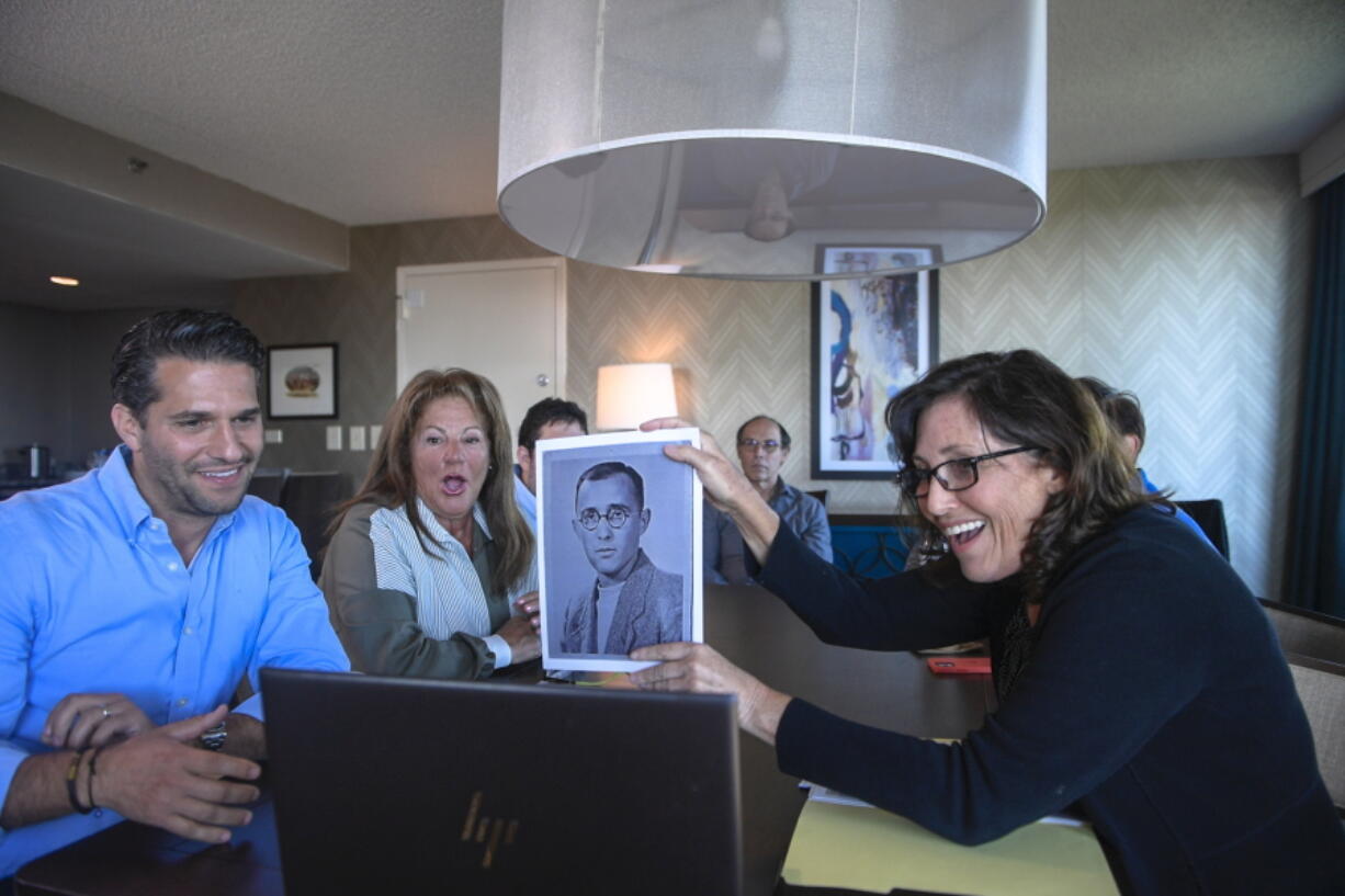 Anna Salton Eisen holds up a photo of Emil Ringel, father of Barbara Ringel, for a Zoom video call during a gathering for families of Holocaust survivors in East Brunswick, N.J., on Sunday, Sept. 26, 2021. Seventy-six years after American soldiers cut down the barbed wire and fulfilled the prisoners' impossible dream of freedom, Eisen brought together survivors' loved ones.