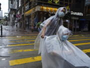 People make their way on an empty street as Typhoon Kompasu passes in Hong Kong Wednesday, Oct. 13, 2021. Hong Kong suspended classes, stock market trading and government services as the typhoon passed south of the city Wednesday.