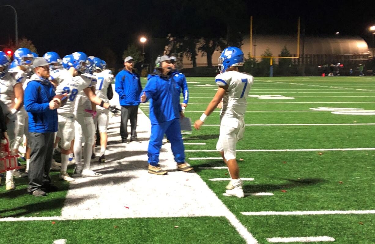 La Center football coach John Lambert, center, greets quarterback Darren Cepeda (7) after a scoring drive on Friday in a 61-14 win over Seton Catholic (Micah Rice/The Columbian)